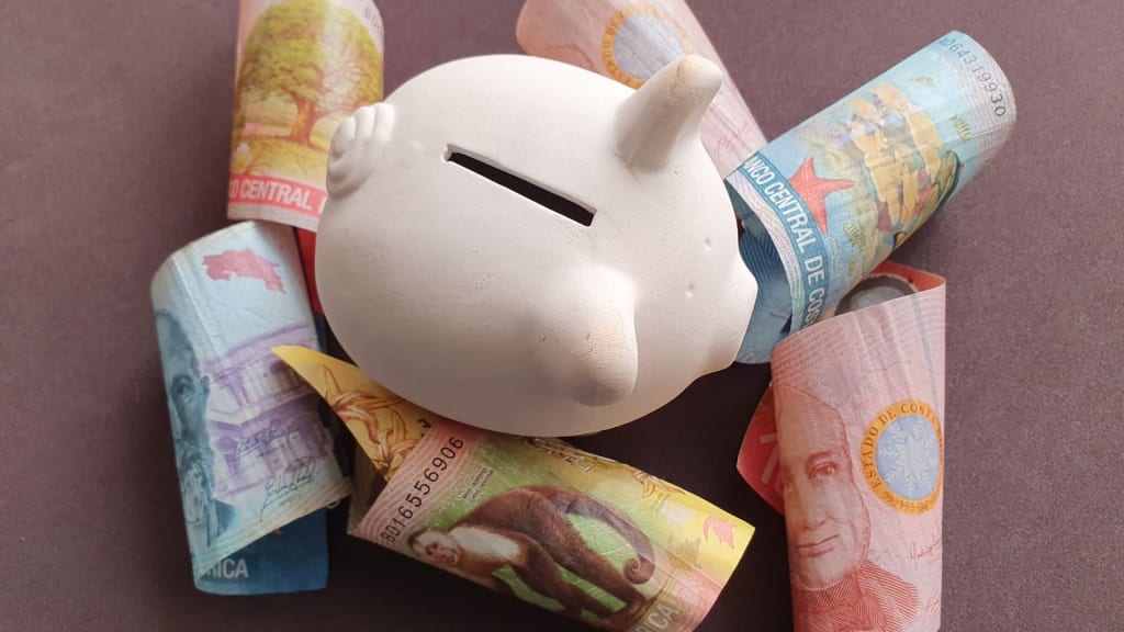 a piggy bank surrounded by colones bills